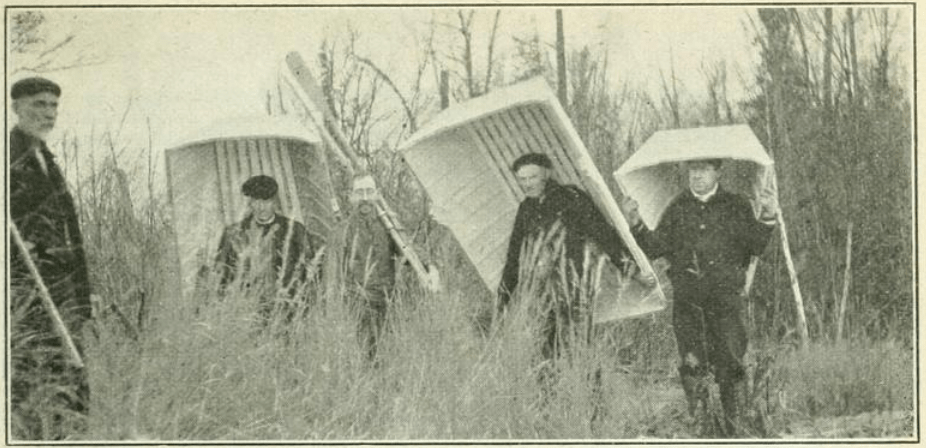 photo of four men carrying three parts of a sectional boat built by C.A. Fleming   he and fellow hunters used in the Algoma district in the early 1900s.